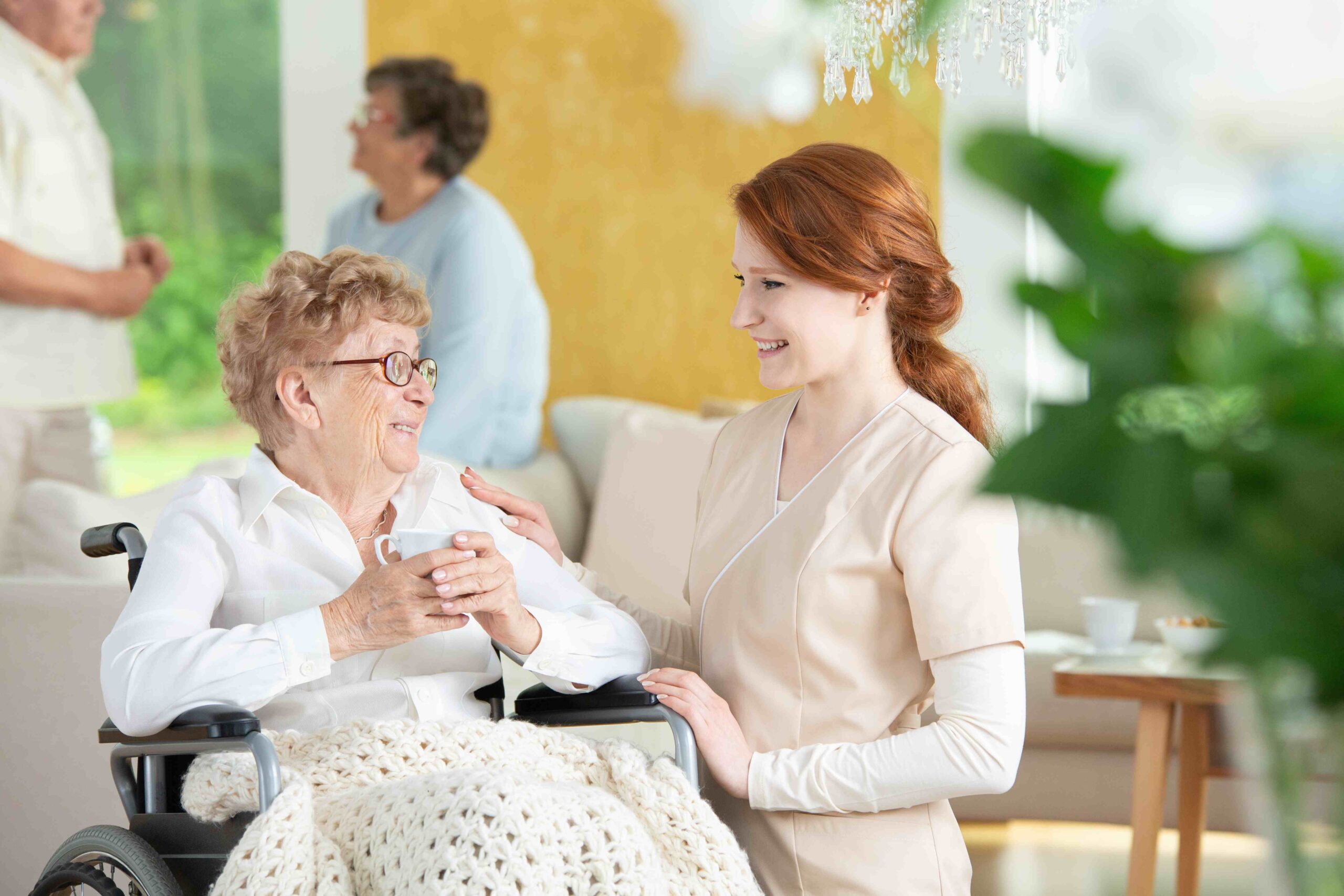 Happy nurse talking with smiling paralysed elderly woman in the